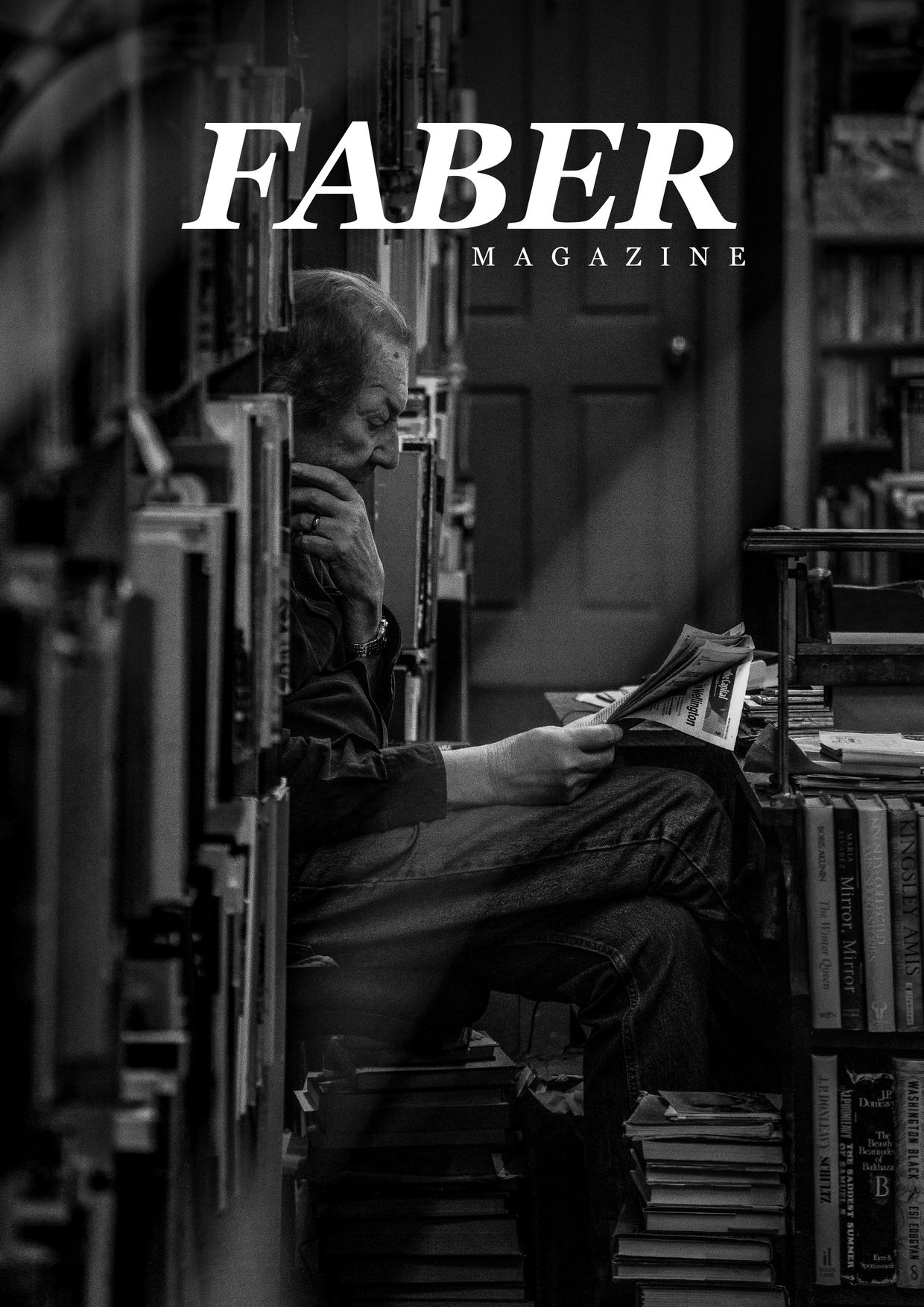 Cover of FABER Issue .00, a black and white photograph of a man reading a newspaper among stacked books in a Wellington bookshop.